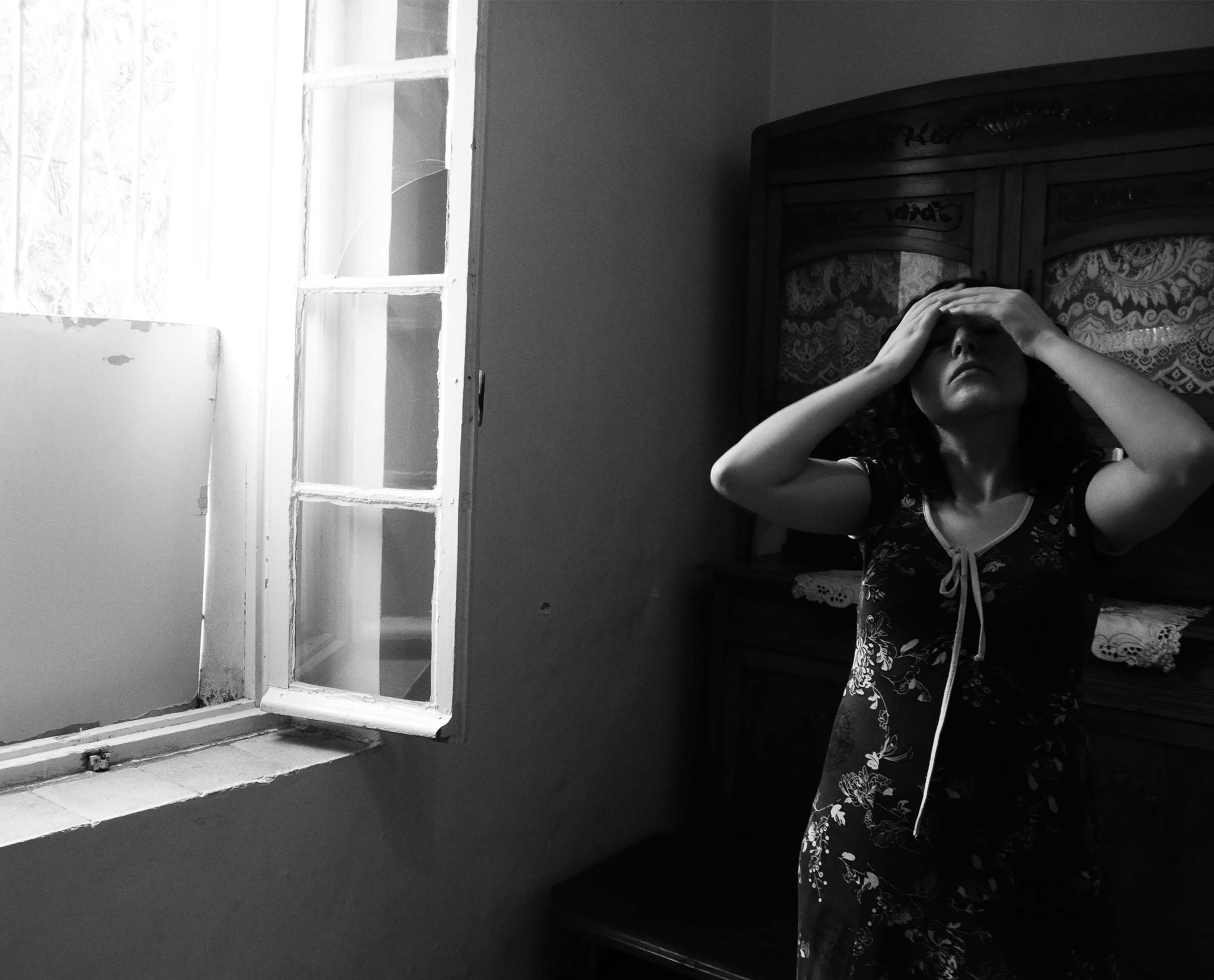 Zoom sur une photo en noir et blanc d'une jeune femme nommée Lilia , les mains sur la tete devant une fenêtre entrouverte  