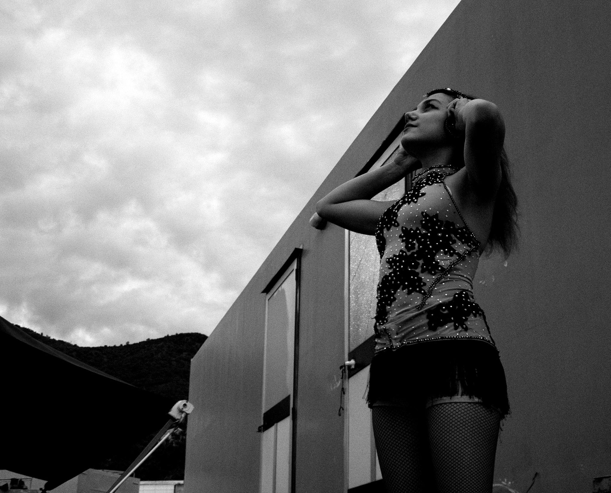 Une photographie en noir et blanc d'une jeune fille , regardant dans le ciel les mains dans ses cheveux .