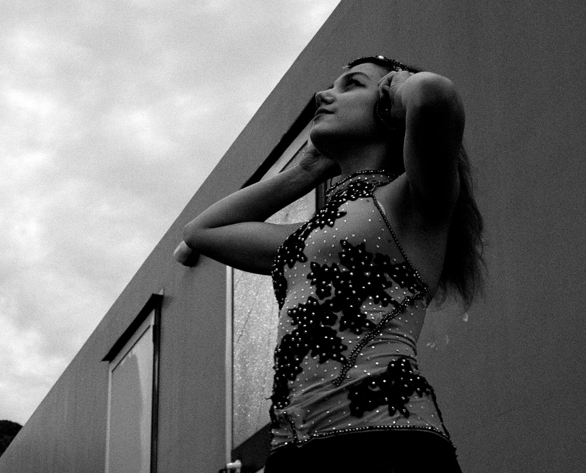 Une photographie en noir et blanc d'une jeune fille , regardant dans le ciel les mains dans ses cheveux .