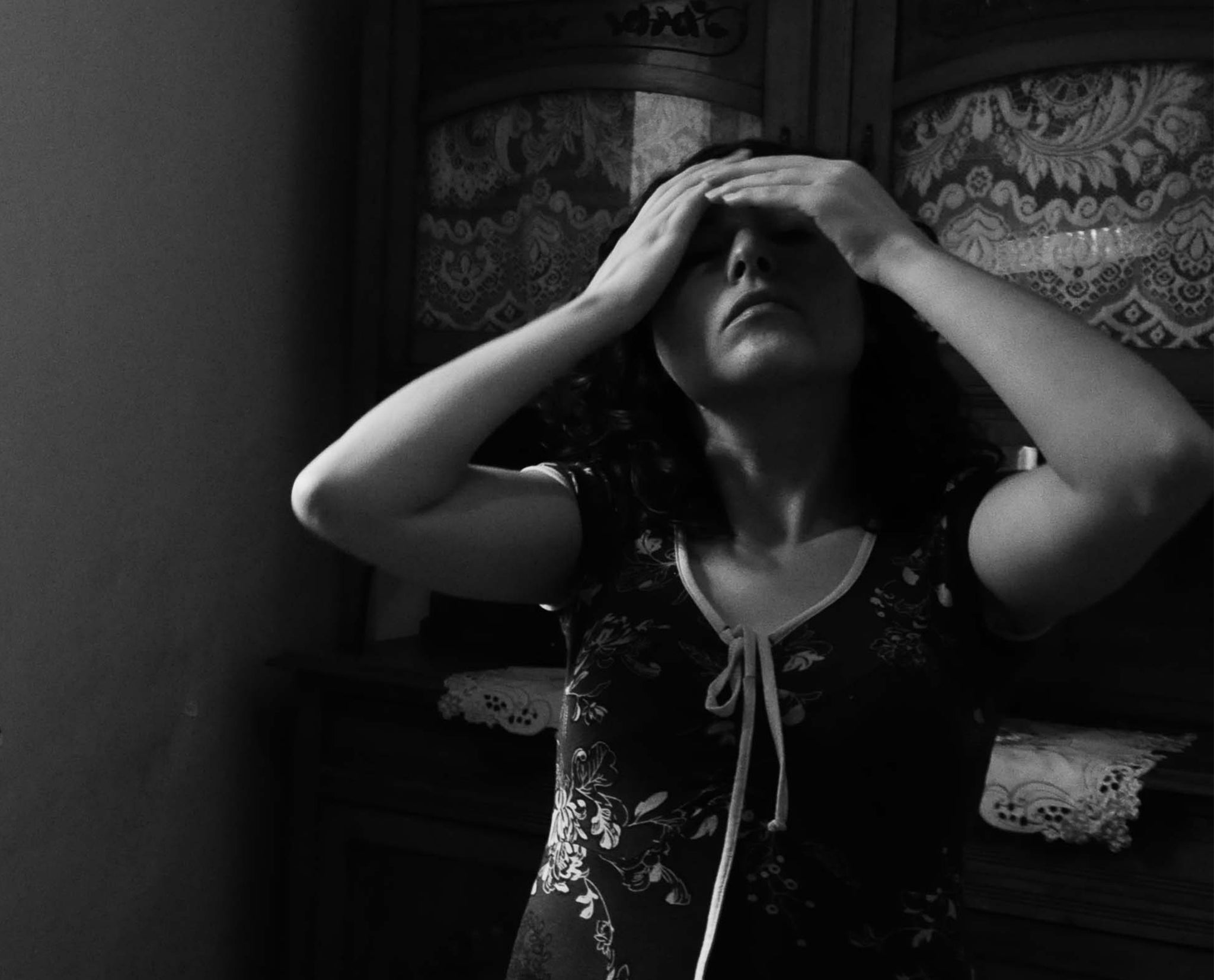 Une photo en noir et blanc d'une jeune femme nommée Lilia , les mains sur le visage. 